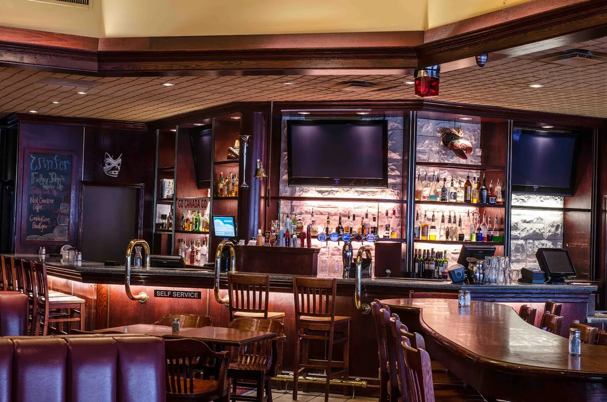 Restaurant bar interior with bottles, TVs, and seating